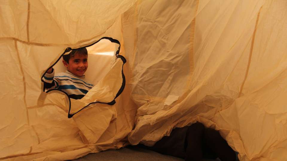 Child peaking through a tarp in Iraq