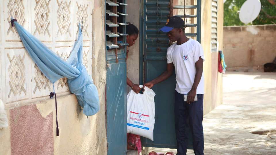 Zakat worker handing off donations in Senegal.