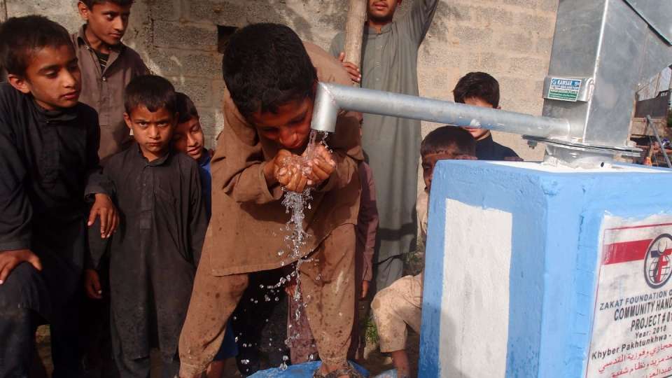 Children in Pakistan take turns drinking from a water well constructed to give them access to clean, safe water. – Zakat Foundation of America photo