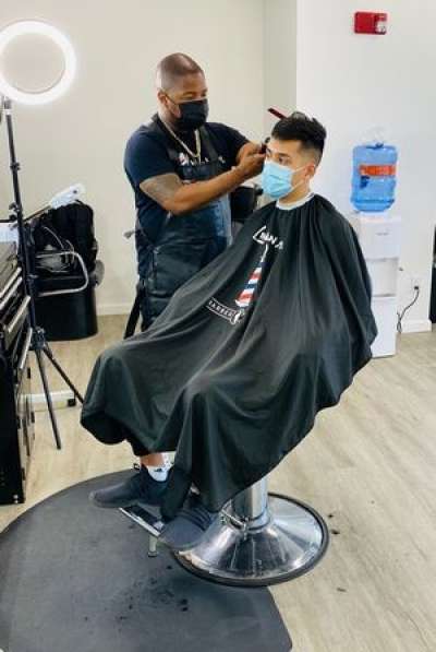 Wilbur Dumas Jr., left, cuts the hair of Jose Gomez. Dumas, 37, of Elgin, started the barbershop because he wanted to give back to the community. - Courtesy of Wilbur Dumas