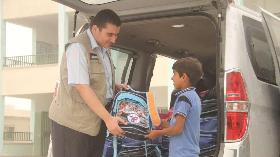 A young boy in Gaza receives a backpack filled with school supplies