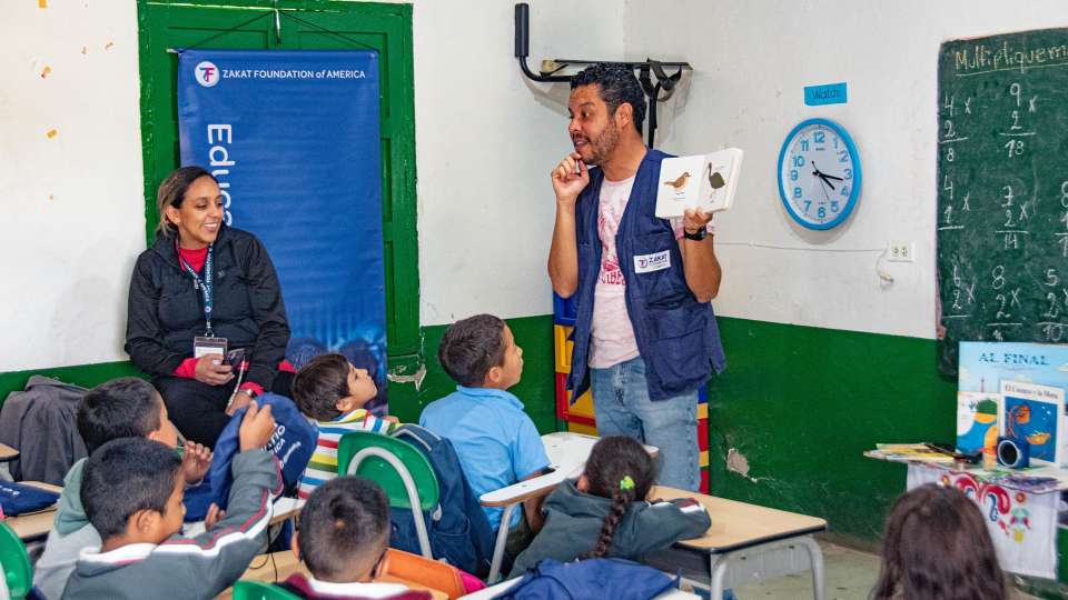 image of zakat rep reading book to kids in impoverished country