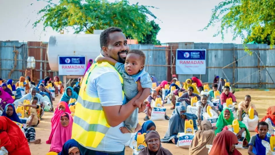 An adorable baby with a ZF representative / ممثل الزكاة يحمل طفلاً