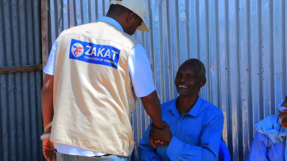 Exchanging warm handshakes / مستفيد يصافح ممثل الزكاة