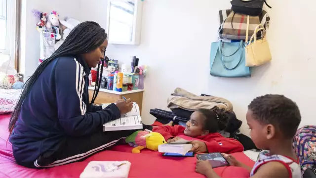 Yudilia Bolano Bello, her daughter Maria and son Brandon read and play video games at a migrant shelter run by the Zakat Foundation in Chicago’s Portage Park neighborhood on Aug. 16, 2024. The shelter opened its doors in May. Manuel Martinez/WBEZ