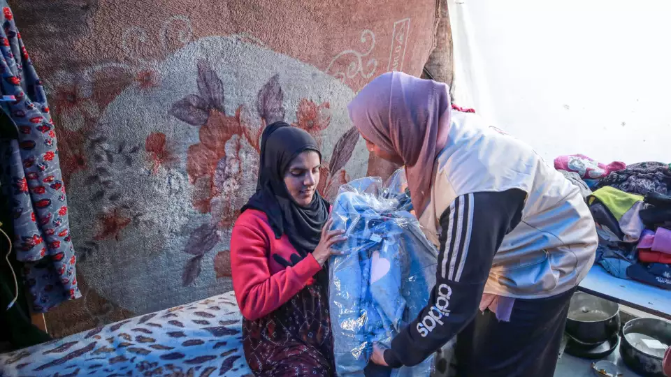 A mother in Gaza receives a warm coat to protect her from the cold