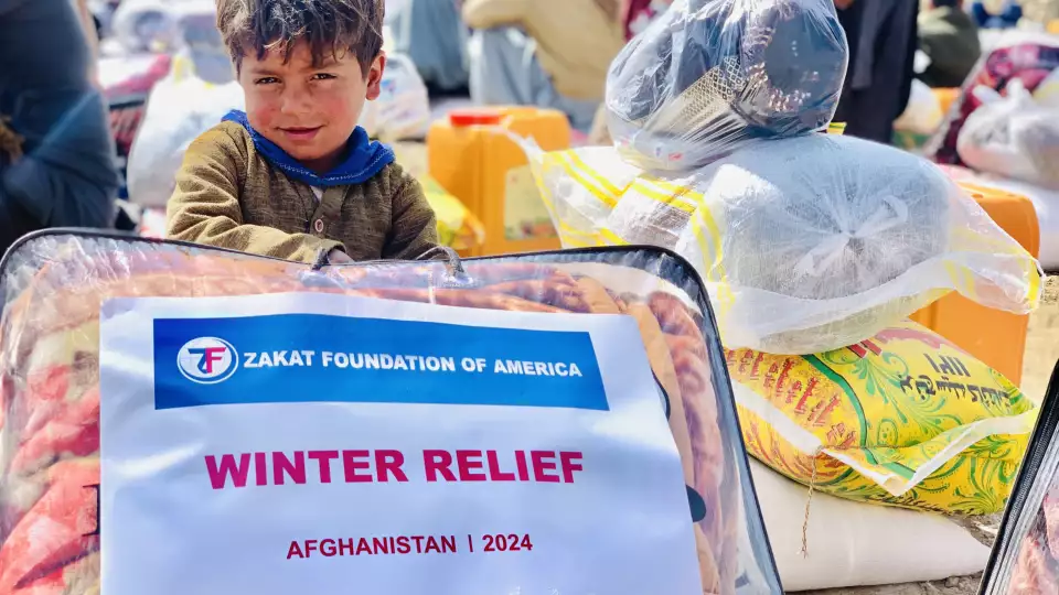 An Afghan boy holds tightly to the winter blanket he received to keep him warm