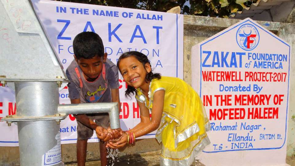 2 children collecting water from a donated Water Well.
