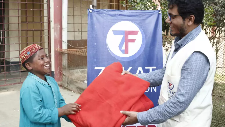 Warmth delivered in Bangladesh as a boy receives winter staples from our field team