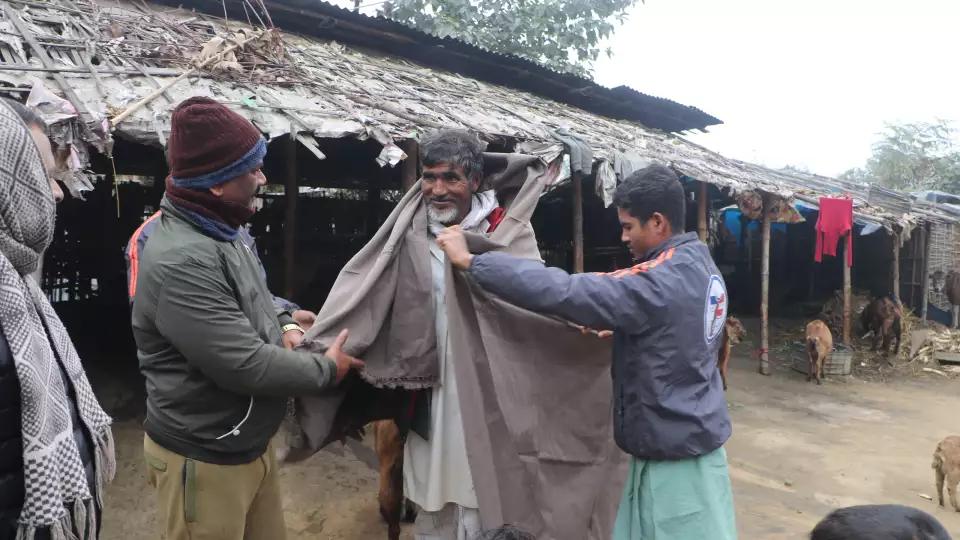 Wrapped with care, a man in Nepal receives a winter shawl