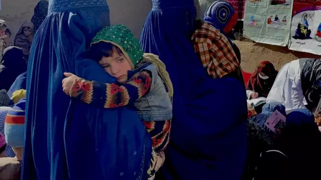 In Coka village, located in Maiwand District, Kandahar Province, Afghanistan, women and children wait to be seen by members of a UNICEF-supported mobile health and nutrition team on December 13, 2021. © UNICEF/UN0567829/AL-JANABI