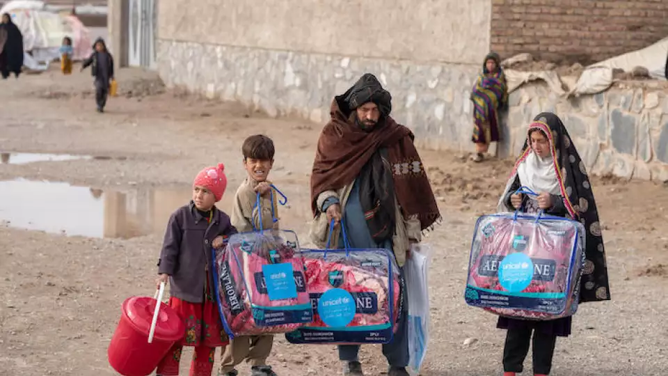 Juma Gul, 32, center, and his family carry blankets and other supplies distributed by UNICEF to protect the most vulnerable from the harsh Afghan winter. © UNICEF/UN0574507/BIDEL
