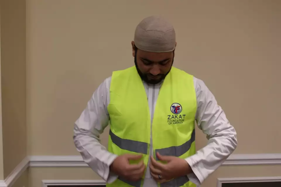 Shaikh Aly of Mecca Center wears a Zakat Foundation of America volunteer vest after giving a speech on the prevalence of hunger and homelessness.