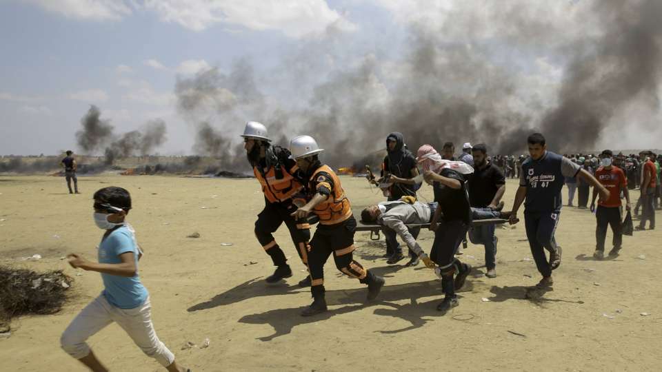 Palestinian medics and protesters evacuate a wounded youth during a protest at the Gaza Strip (AP Photo/Adel Hana)