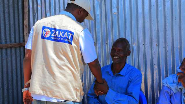 Zakat Rep shaking hands with support recipient