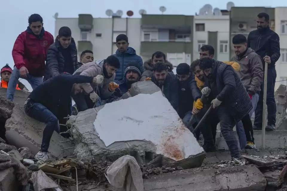 People search for survivors among the debris in a destroyed building in Adana, Turkey, on Feb. 6. (Khalil Hamra / AP)