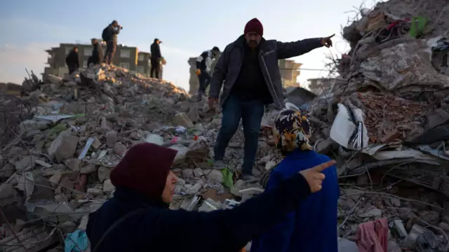 Local residents walk on the rubble of collapsed buildings as rescue workers continue the search for victims of the earthquake in Antakya, Turkey. Rescue crews on Saturday pulled more survivors, including entire families, from toppled buildings despite diminishing hopes as the death toll of the enormous quake that struck a border region of Turkey and Syria a week ago continue to rise. Lefteris Pitarakis/AP