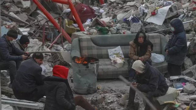 KAHRAMANMARAS, TURKEY – FEBRUARY 10: People sit around a fire among the rubble of collapsed building on February 10, 2023 in Kahramanmaras, Turkey. A 7.8-magnitude earthquake hit near Gaziantep, Turkey, in the early hours of Monday, followed by another 7.5-magnitude tremor just after midday. The quakes caused widespread destruction in southern Turkey and northern Syria and were felt in nearby countries. (Photo by Aziz Karimov/Getty Images)
