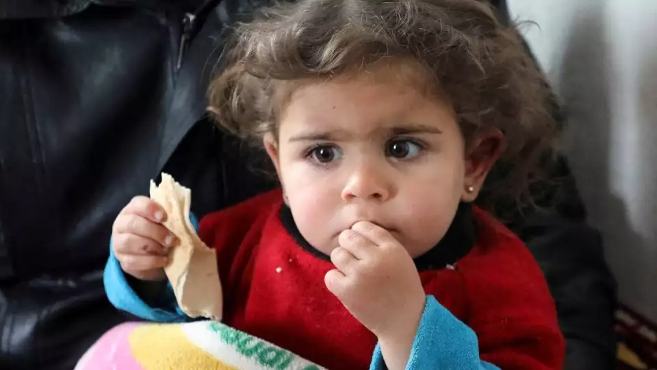 Raghad Ismail, a Syrian toddler who was rescued from rubble of a collapsed building after the earthquake, sits on her uncle's lap at his home in rebel-held Azaz, Syria. Reuters