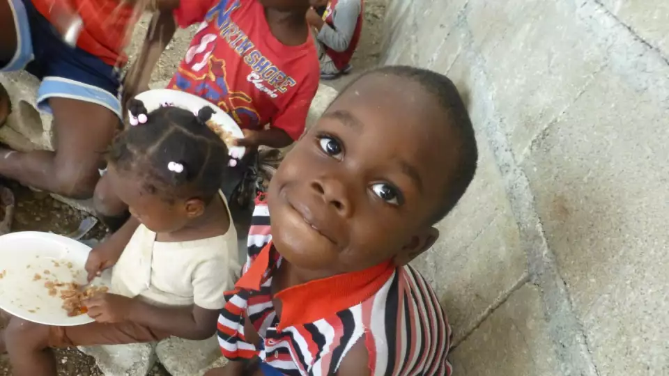 a sweet child enjoys a warm meal with his community