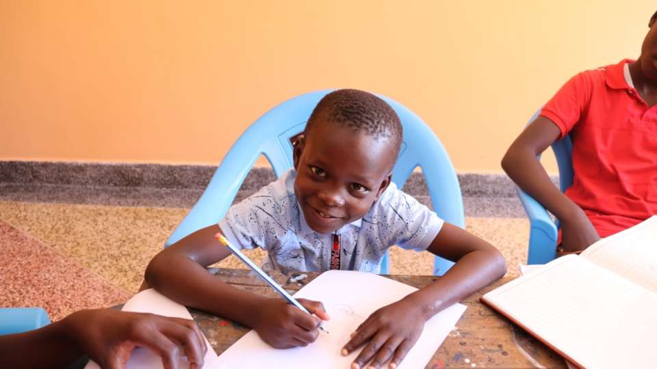 An orphan creates art in class in Kenya
