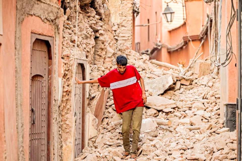 image of survivor with red shirt walking through morroco earthquake rubble