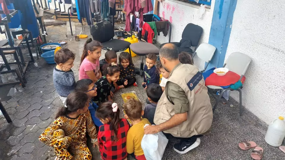 Volunteer sits with children while distributing meals