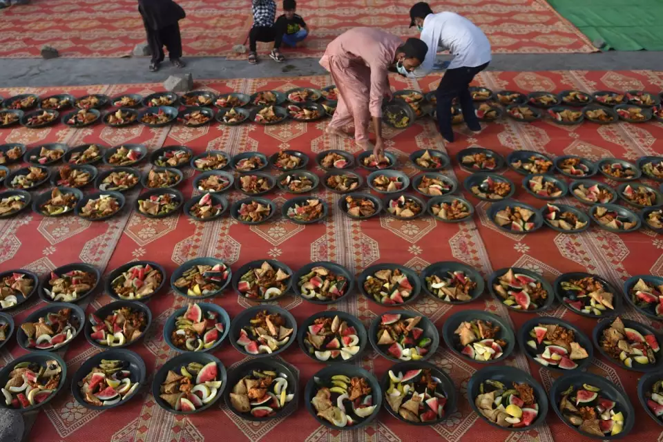 Volunteers prepare Iftar food plates for Muslim devotees to break their fast during the holy month of Ramadan along a street in Karachi on April 23, 2021. RIZWAN TABASSUM, AFP Via Getty Images