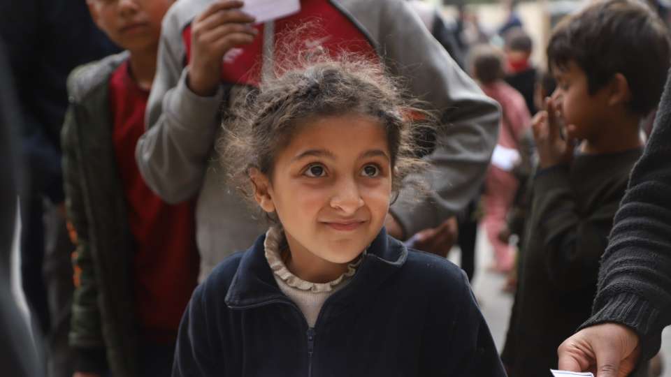 A child in Gaza holds her hot meal thanks to your support