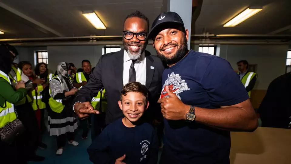 Mayor Brandon Johnson poses for a photo with migrants Omar and Osmar Ortiz from Venezuela as migrants were welcomed with a dinner at the recently opened migrant shelter at St. Bartholomew Catholic Church in Portage Park on June 11, 2024. Credit: Colin Boyle/Block Club Chicago