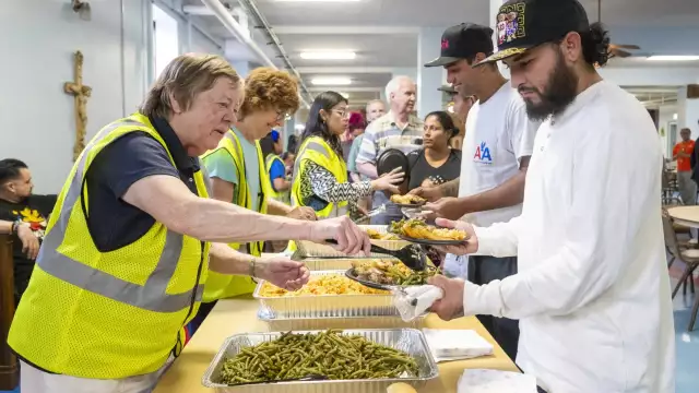 Volunteers with the Zakat Foundation serve food to asylum-seekers in the basement of St. Bartholomew Catholic Church in the Portage Park neighborhood Tuesday. Months after the city and Archdiocese of Chicago began talks about opening a shelter at the shuttered school, residents have moved in.Tyler Pasciak LaRiviere/Sun-Times