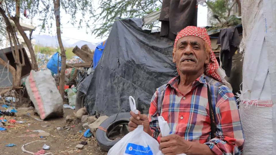 A Yemeni man accepts food packages in his community