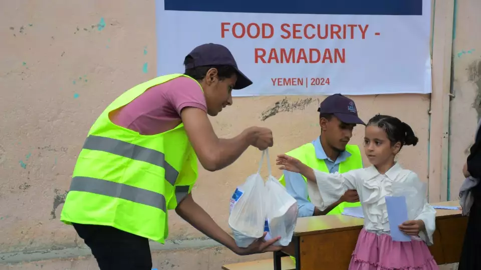 A Yemeni school girl joyfully accepts a Ramadan food package