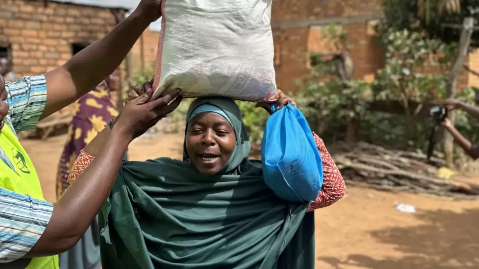 A Tanzanian woman is helped by our team rep with a food package during distribution.