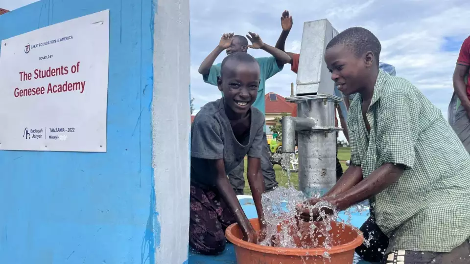Smiles all around as students play with fresh water at our sponsored pump thanks to a generous donor.