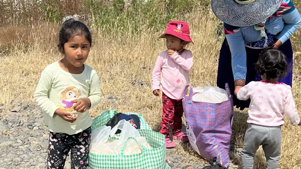 Children gather around their mother to eat snacks from our food packages.