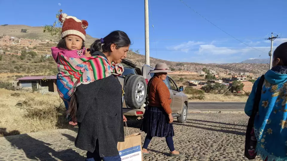 A young Bolivian girl is carried by her mother after leaving our food distribution site.