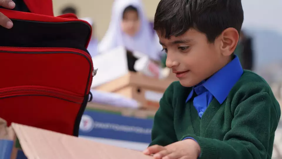 A young sponsored orphan from Pakistan receives essentials for school.