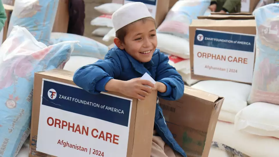 An orphaned Afghan boy sits with an expression of relief on his face after receiving essential supplies from supporters like you.