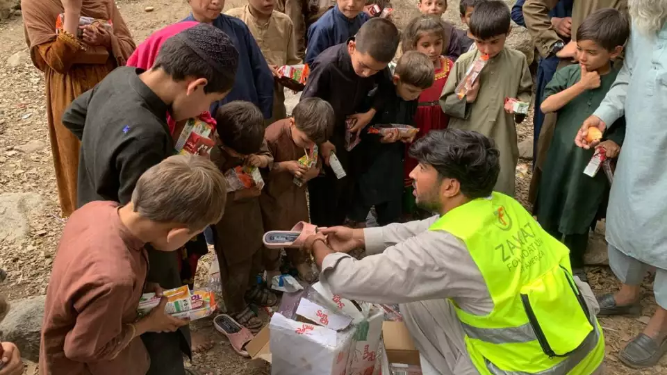 Children gather around our team member in Afghanistan for shoes and food